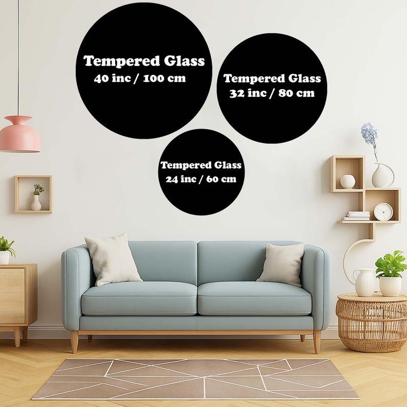 Op de afbeelding: Drie zwarte, cirkelvormige wandkunstwerken van gehard glas in verschillende maten: 40 inch (100 cm), 32 inch (80 cm) en 24 inch (60 cm). Elk stuk heeft witte tekst die de grootte aangeeft. De kunst wordt boven een blauwe bank getoond.