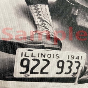 May include: Monochrome image featuring an Illinois license plate from 1941, with the registration number 922 933. A leg and boot are partially visible in the shot.