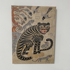 May include: An antique-style canvas print featuring a tiger with black stripes and yellow eyes, surrounded by birds and smaller tigers. The artwork has a vintage aesthetic with faded colors and Asian-inspired elements.