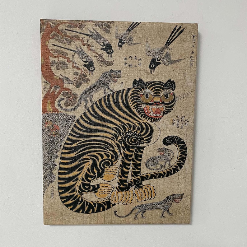 May include: An antique-style canvas print featuring a tiger with black stripes and yellow eyes, surrounded by birds and smaller tigers. The artwork has a vintage aesthetic with faded colors and Asian-inspired elements.