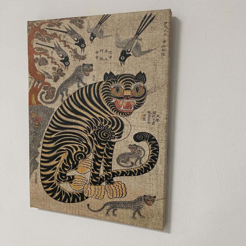 May include: A vintage canvas print featuring a tiger with black stripes and yellow eyes, surrounded by other tigers and birds. The artwork has a traditional Asian style with faded colors and intricate details.