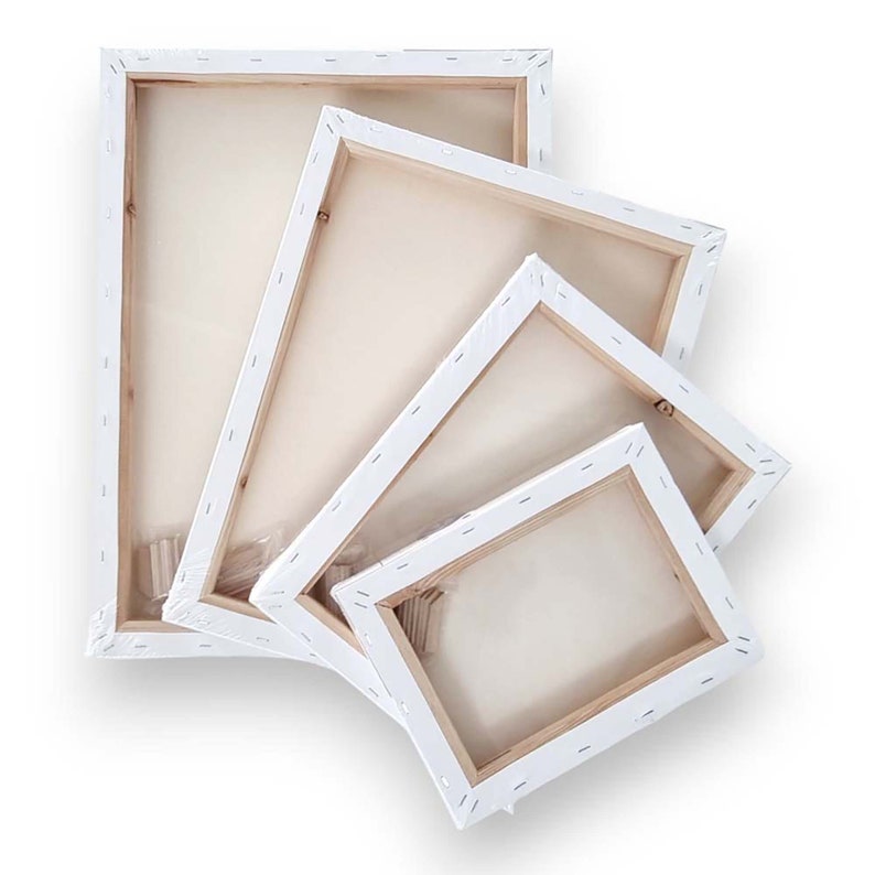 May include: Four white-framed canvas art panels of different sizes are stacked, revealing their backs. The wooden frames are visible, and the canvas is wrapped in clear plastic. The arrangement suggests a set of blank canvases for painting or art projects.