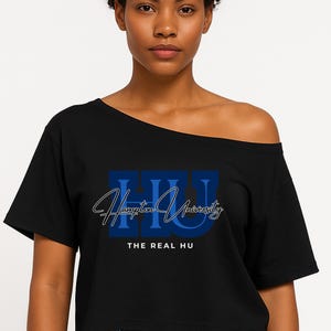 Puede incluir: Camiseta negra con hombros descubiertos con el texto "HU Hampton University" en azul y blanco. Debajo del texto está "THE REAL HU" en letras mayúsculas blancas. La camiseta tiene mangas cortas.