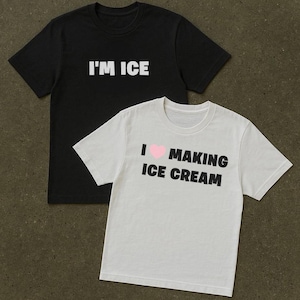 Könnte beinhalten: Zwei T-Shirts, eines schwarz und eines weiß, mit Text. Das schwarze Shirt trägt in weißen Blockbuchstaben die Aufschrift "I'M ICE". Das weiße Shirt trägt "I ♥ MAKING ICE CREAM" mit einem rosa Herz.