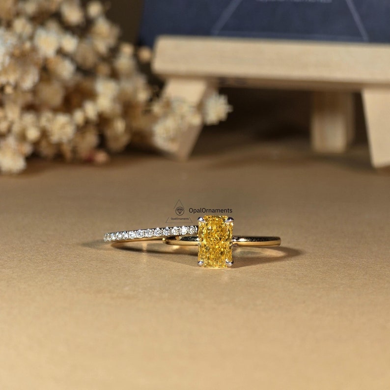 May include: A yellow gold engagement ring set with a rectangular yellow diamond and a matching band with smaller diamonds.
