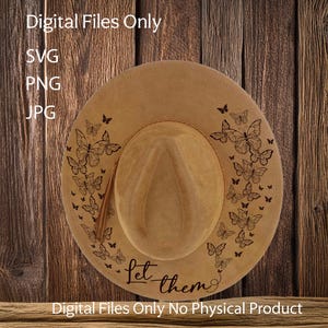May include: A brown cowboy hat with a black butterfly design and the text "Let them" on the brim. The hat is on a wooden background.