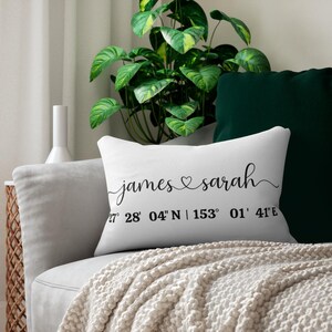 May include: White cushion with black text that reads "james ♥ sarah" and coordinates "27° 28' 04" N | 153° 01' 41"E".