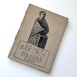 Może przedstawiać: Vintage książka z beżową okładką. Okładka zawiera czarno-białą ilustrację osoby w płaszczu. Tytuł książki, "ERNST BARLACH ein selbst erzähltes Leben", jest wydrukowany w prostokątnej ramce.