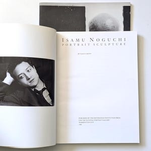 May include: Open book with the title "ISAMU NOGUCHI PORTRAIT SCULPTURE" by Nancy Grove. The book is open to a black and white portrait of a man. The book is published by the Smithsonian Institution Press for the National Portrait Gallery, Washington City.