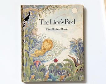 Può includere: Libro per bambini vintage intitolato "The Lion's Bed" di Diane Redfield Massie. La copertina presenta un leone in una scena della giungla con un rigoglioso fogliame verde, un tucano e un elefante. Il libro ha un aspetto usurato e invecchiato.