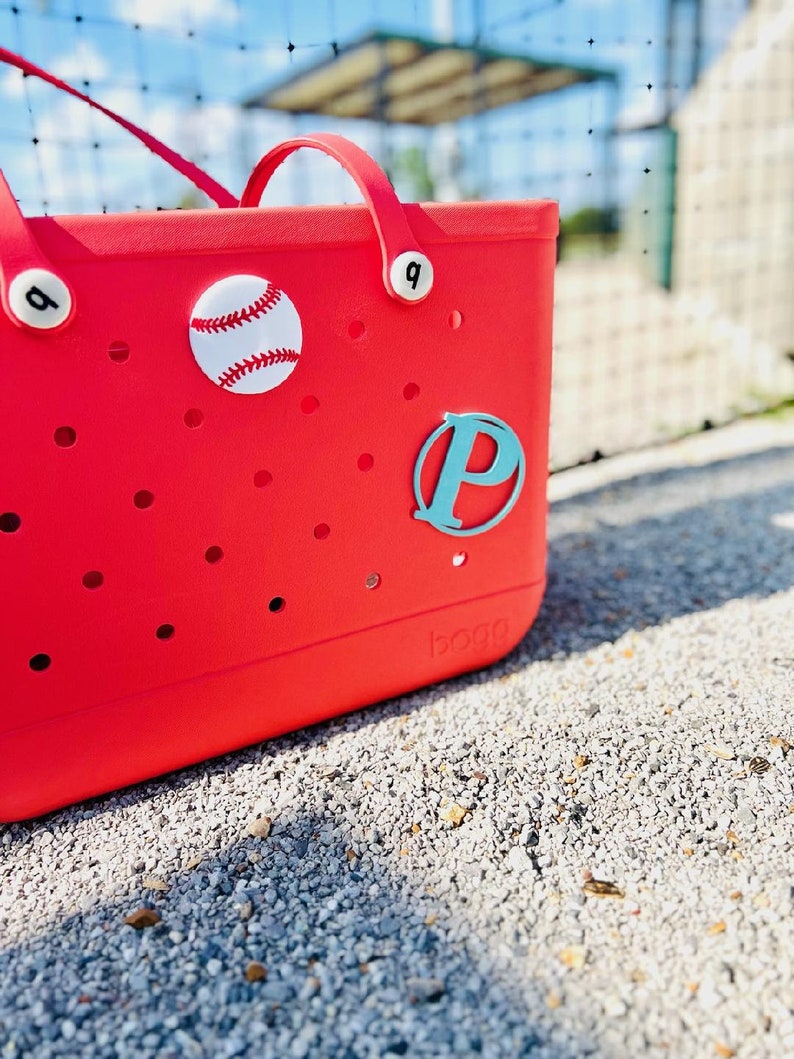 May include: Red tote bag with a white baseball and a turquoise letter "P" on the front. The bag has a white logo that says "BOGO" on the bottom.