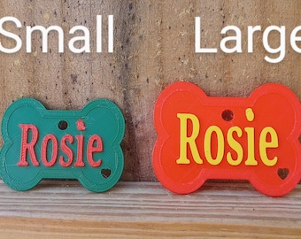 May include: Two dog bone-shaped name tags, one green and one red, both with the name "Rosie" in a different color. The green tag is labeled "Small" and the red tag is labeled "Large".