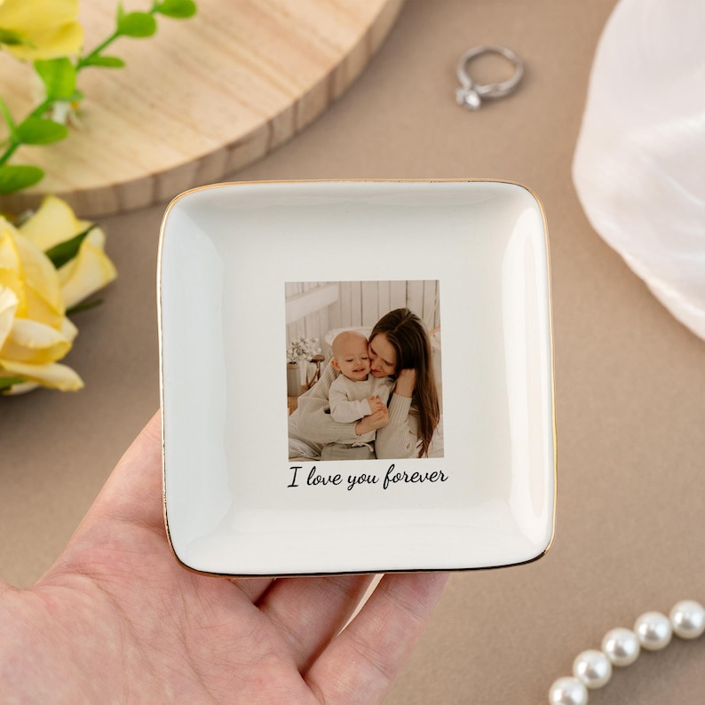 Puede incluir: Plato de cer&aacute;mica blanca para joyas con un borde dorado. El plato presenta una foto de una madre y un hijo con el texto "I love you forever" impreso debajo de la foto.