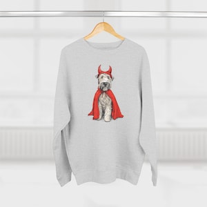 May include: A light gray sweatshirt featuring a dog dressed as a devil. The dog wears a red cape and a red devil horn headband. The image is a whimsical illustration, perfect for Halloween or pet lovers.