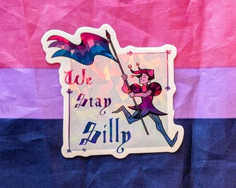 May include: A sticker featuring a cartoon jester holding a flag with pink, blue, and purple colors. The sticker has the words "We Stay Silly" in a decorative font. The jester is wearing a purple and pink outfit.