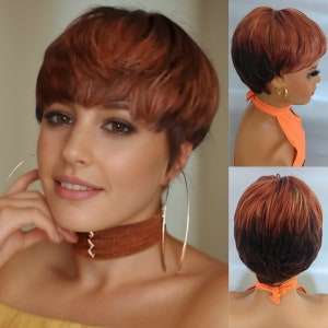 Op de afbeelding: Een kort, stoppig pruik met een donkerbruine basis en roodbruine highlights. De pruik is gestyled in een pixie-cut met lagen en een scheiding aan de zijkant. De pruik wordt getoond op een mannequinhoofd met een feloranje haltertop.