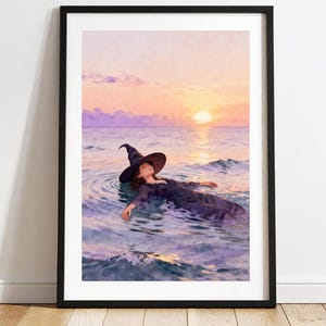 May include: Framed art print depicting a woman in a witch hat floating in ocean water at sunset. The artwork is in a watercolour style with soft colours of purple, orange, and yellow. The text "Mystic Moon ART GAL" is at the top.
