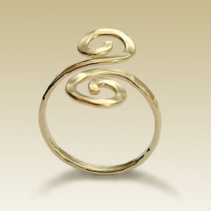May include: A gold ring with a hammered finish and two spiral designs. The spirals are connected and extend above the ring band.