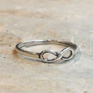 Puede incluir: Un anillo de plata con forma de infinito con un diseño sencillo.