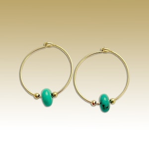 May include: A pair of gold hoop earrings with a turquoise bead on each hoop.