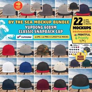 May include: A collection of classic snapback cap mockups in a variety of colours, including red, white, and navy blue. The image shows 22 different cap designs, with the text "BY THE SEA MOCKUP BUNDLE" and "YUPOONG 6089M CLASSIC SNAPBACK CAP".