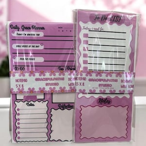 Könnte beinhalten: Ein Set aus vier rosa und weißen Notizblöcken, jeweils mit einem anderen Design. Die oberen beiden Notizblöcke sind mit "Daily Grace Planner" und "To Do List" beschriftet. Die unteren beiden Notizblöcke sind mit "Notes" und "Reflection" beschriftet. Jeder Notizblock ist 12,7 x 20,3 cm groß.