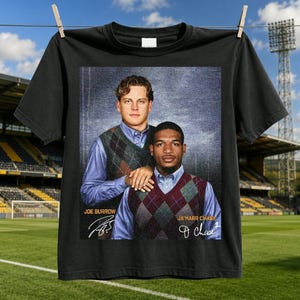 May include: A black t-shirt featuring a graphic print of Joe Burrow and Ja'Marr Chase wearing argyle sweater vests over light blue button-down shirts. The text "JOE BURROW" and "JA'MARR CHASE" appears with their respective signatures below them.