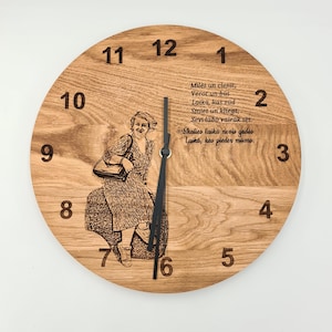 Könnte beinhalten: Eine runde Wanduhr aus Holz mit hellbraunem Finish. Das Zifferblatt der Uhr hat eingravierte Ziffern und ein Bild einer Frau. Die Zeiger der Uhr sind schwarz. Text ist auf das Zifferblatt graviert.