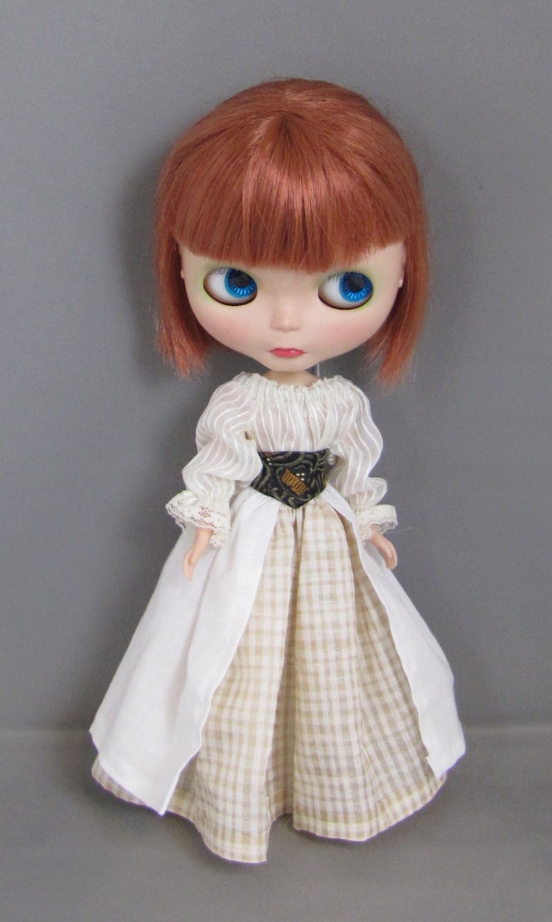May include: A doll with red hair wearing a white and beige gingham dress with a white lace trim and a black belt.