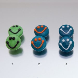 May include: Eight smiley face glass beads in four different color combinations: green with black, teal with orange, teal with white, and green with white.