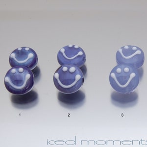 May include: Four pairs of glass smiley face beads. Two pairs are blue with white smiley faces, and two pairs are brown with white smiley faces.