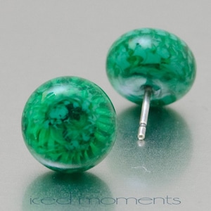 May include: A pair of green and white stud earrings with a silver post. The earrings are round and have a marbled appearance.