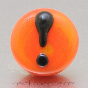 Könnte beinhalten: Orangefarbene Glaskugel mit einem schwarzen Ausrufezeichen.