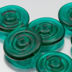 May include: Five teal blue glass buttons with a swirling design. The buttons are round and have a glossy finish.
