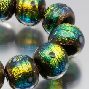 Op de afbeelding: Een streng iriserende glazen kralen met een zwart, groen en gouden kleurenschema. De kralen hebben een gespikkeld, getextureerd oppervlak.