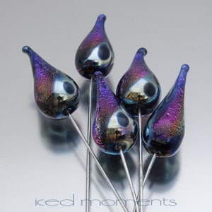 May include: Five iridescent glass teardrop beads with black accents on silver wire.