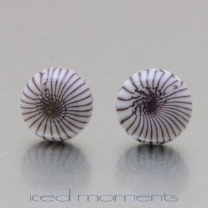May include: A pair of white and purple glass earrings with a spiral design.