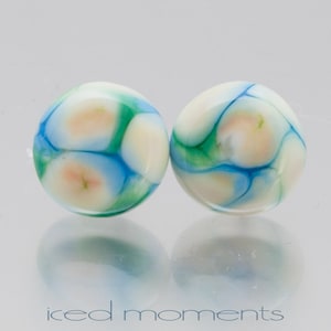 May include: A pair of round, white earrings with blue and green marbling. The earrings are made of glass and have a smooth, glossy finish.