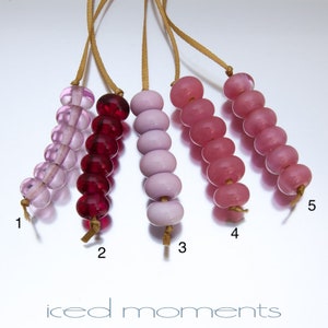 May include: Five strands of glass beads, each with a different color gradient. The strands are numbered 1 through 5. The beads are pink, purple, and red.
