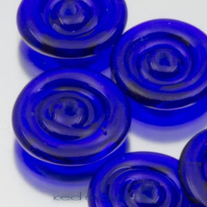 May include: A set of six cobalt blue glass buttons with a swirling design. The buttons are round and have a smooth, glossy finish.