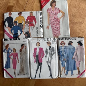 May include: A collection of five paper sewing pattern envelopes from brands Butterick, See & Sew, and New Look. The envelopes feature illustrations of various garments including dresses, blazers, skirts, and tops, with printed text identifying brand names.