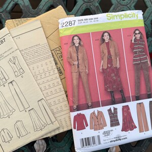 May include: A Simplicity 2287 sewing pattern envelope for size BB 20W-28W, featuring illustrations of a blazer, pants, skirt, and top. The front shows three models wearing these garments in tan, red, and patterned fabrics, with technical line drawings.