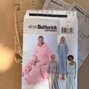 May include: A Butterick sewing pattern packet, featuring a pink hooded outfit, a blue hooded robe, and a gray two-piece set. The packet is labeled "4038 FAST & EASY" and includes size information.