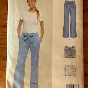 May include: A sewing pattern package from New Look, featuring a woman modeling blue striped pants with a tie waist and a white t-shirt. The package also shows illustrations of shorts. The text on the package reads "NEW LOOK" and "N6606".