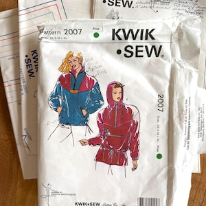 May include: A Kwik Sew pattern envelope for pattern 2007, featuring illustrations of two jackets in sizes XS-S-M-L-XL. The white paper envelope displays black text, a barcode, and hand-written notes in blue ink. The illustrations show a blue and pink jacket and a solid pink hooded jacket.