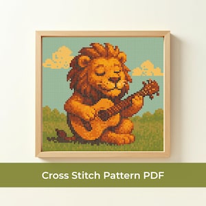 May include: A framed cross-stitch pattern featuring a cartoon lion playing a ukulele. The lion is rendered in shades of orange and brown, with a green and blue pixelated background. The text "Cross Stitch Pattern PDF" is at the bottom.