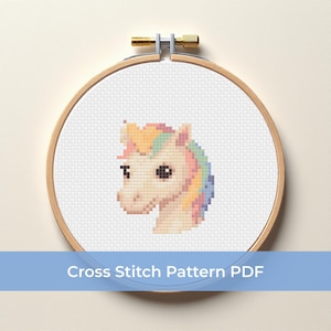 Puede incluir: Un patrón de punto de cruz de la cabeza de un unicornio, con un cuerpo color crema y una melena con colores arcoíris pastel. El diseño está dentro de un bastidor de bordado de madera. El texto "Cross Stitch Pattern PDF" se muestra en una pancarta azul.
