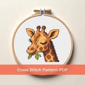 May include: A cross-stitch pattern of a giraffe eating leaves, displayed in a wooden embroidery hoop. The giraffe is brown and tan with dark brown spots. The text "Cross Stitch Pattern PDF" is displayed on an orange banner.