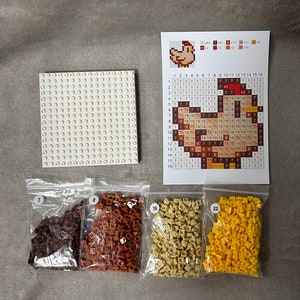 Op de afbeelding: Een witte plastic basisplaat voor een moza&iuml;ekset, samen met vier zakken met gekleurde plastic kralen. De zakken zijn gelabeld met de nummers 7, 8, 16 en 20. Een diagram toont de lay-out van de moza&iuml;ek, die een kip voorstelt.