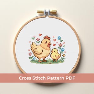 Può includere: Schema a punto croce con una gallina e un pulcino, circondati da fiori e cuori, ricamato su tessuto bianco. Il disegno è racchiuso in un telaio da ricamo in legno. Il testo "Cross Stitch Pattern PDF" è visualizzato in basso.